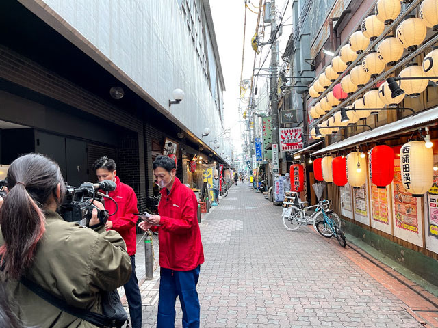 居酒屋の前で真剣に台本をチェックする二人