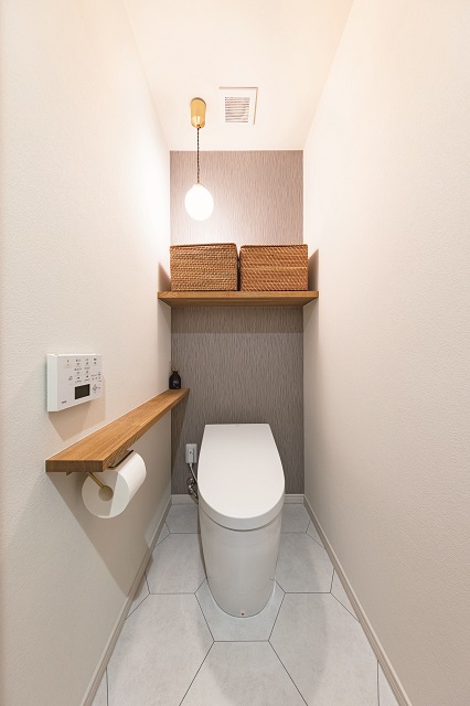 2色の壁紙と、床に六角のタイルを採用したトイレはシックな雰囲気。ペンダント照明で優しい雰囲気を高め、ゲストも気持ちよく使えるように整えた